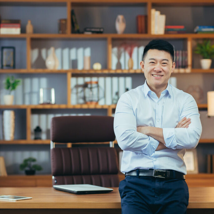 Portrait of a successful businessman working in a classic office, Asian smiling and happy looking at camera with arms crossed